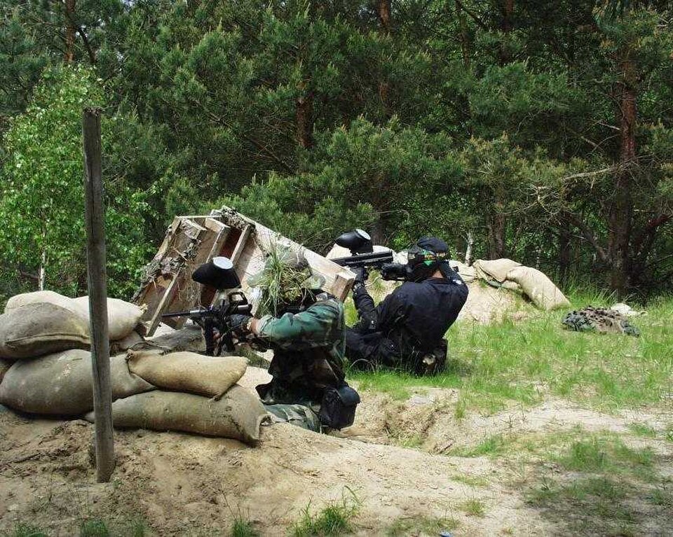 Partie de paintball en forêt, joueurs derrière des sacs de sable (photo d'illustration, 856x684)