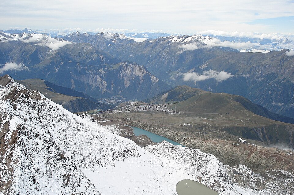 Vue du Pic Blanc sur l'Alpe d'Huez et la plaine du Bourg-d'Oisans : le trajet du Grand vol. Paysage 1600x1064, licence vérifiée via l'API Commons le 18/10/2026.