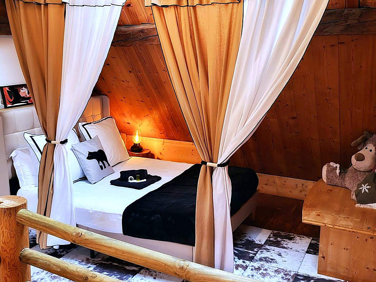 Chambre de caractère du Cosy Lodge avec lit à baldaquin en rondins