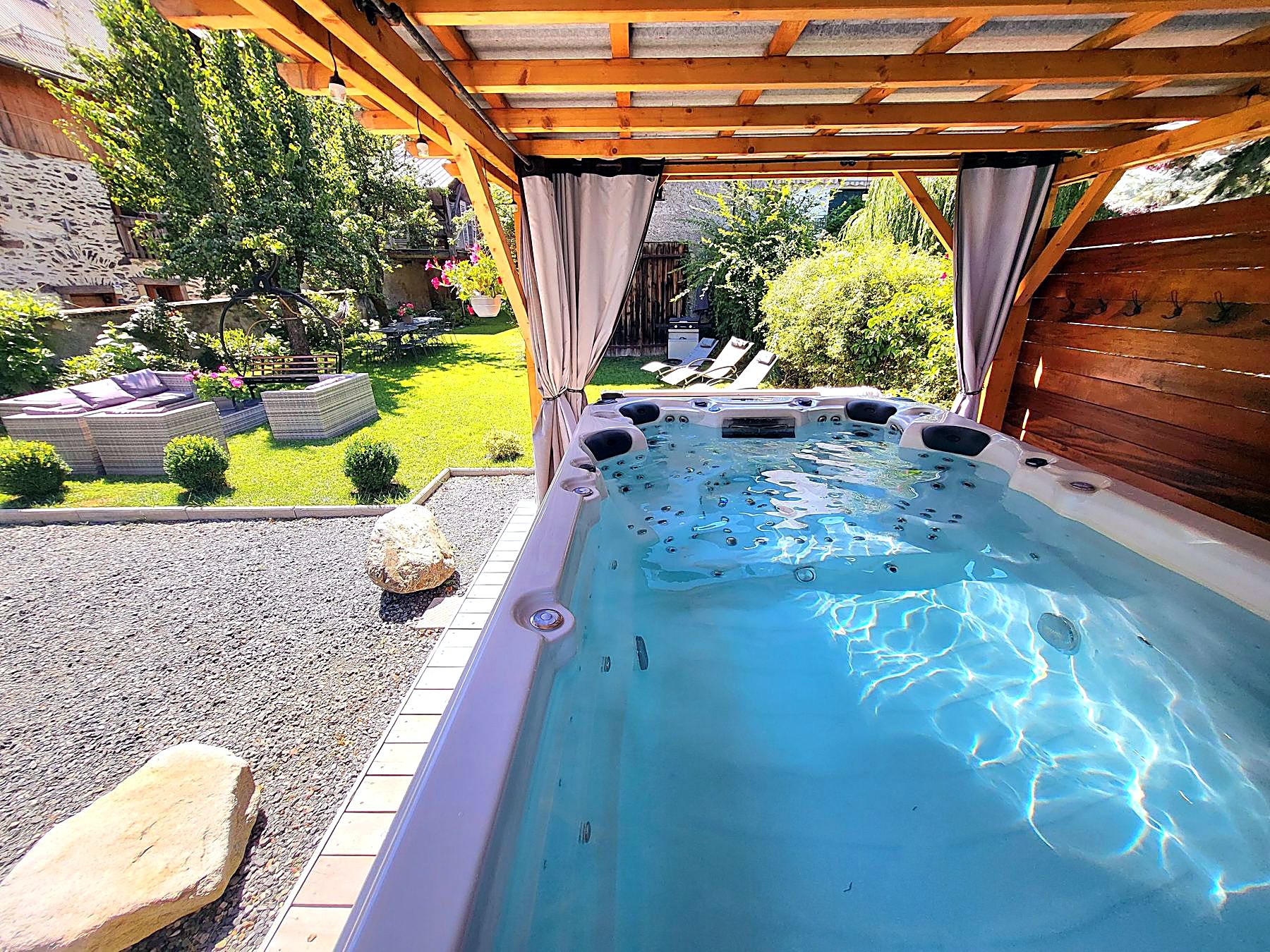 Le spa de nage chauffé du Cosy Lodge sous pergola, face au jardin, au Bourg-d'Oisans