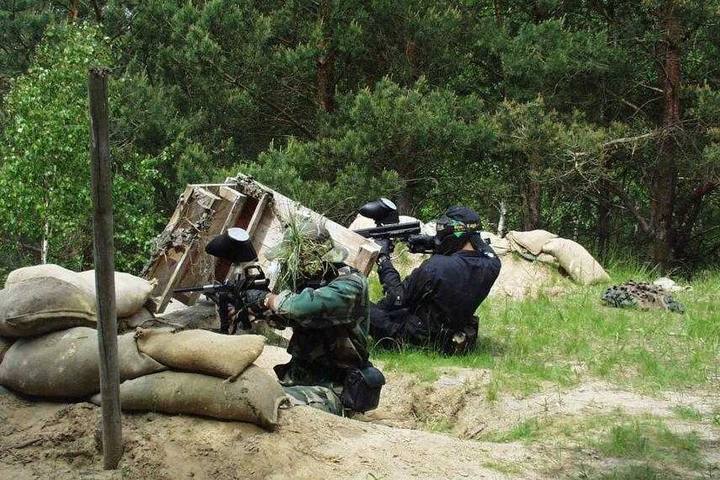 Partie de paintball en forêt, joueurs derrière des sacs de sable (photo d'illustration, 856x684)